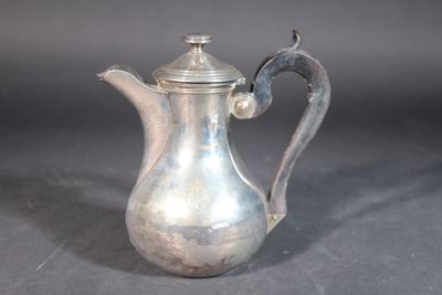a silver coffee pot with a handle on a table