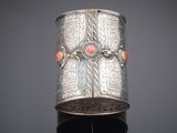 an antique silver bracelet with coral stones on a stand