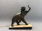 un éléphant coiffé d'un chapeau, posé sur un socle en marbre