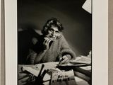 photographie en noir et blanc d'une femme assise à un bureau avec une calculatrice