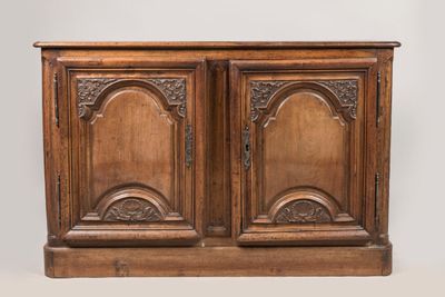 une vieille armoire en bois à deux portes, ornée de sculptures sur la façade