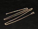 three gold chains on a black surface