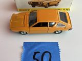 une petite voiture miniature posée à côté d'un morceau de tissu sur une table