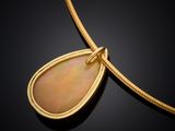 a yellow gold pendant with an oplite stone on a black background