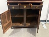 une armoire en bois à deux portes, ouverte sur le sol