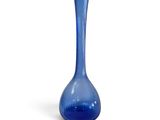 un vase en verre bleu posé sur une surface blanche