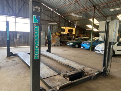 un chariot élévateur dans un garage, avec des voitures garées en arrière-plan