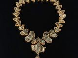 un collier en or orné d'une pierre verte et blanche au centre