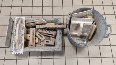 a bucket full of tools sitting on a tiled floor