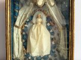 a picture of a doll in a gold frame on a table