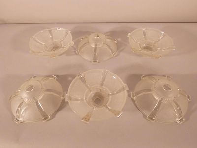 six clear glass dishes with lids on a white surface
