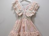 pink and white dress hanging on a hanger against a white wall