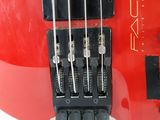 a close up of a red electric guitar with four strings