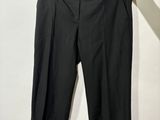 un pantalon noir suspendu à un cintre devant un mur blanc