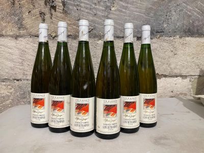 six bottles of wine sit on a table in front of a stone wall