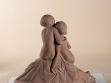 a sculpture of two people hugging each other on a table