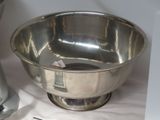 a silver bowl sitting on top of a table next to a blender