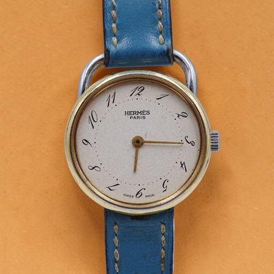 une image représentant une montre-bracelet avec un bracelet bleu sur un fond jaune