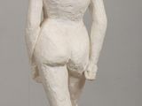 a white statue of a man standing on a wooden table