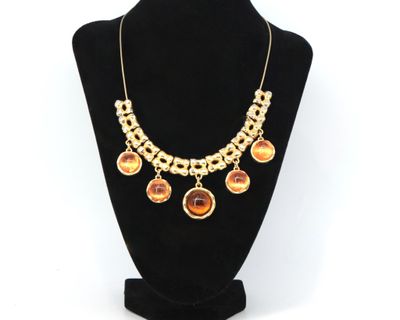 un collier en or orné de pierres orange sur un mannequin noir