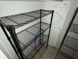 a black wire shelf in the corner of a room