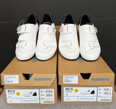 trois paires de chaussures blanches posées sur une boîte en carton