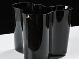 two black vases on a white table with a black background