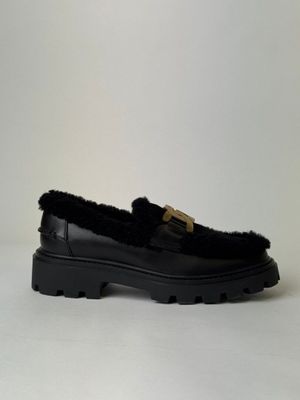 un mocassin noir orné d'une boucle dorée sur le dessus