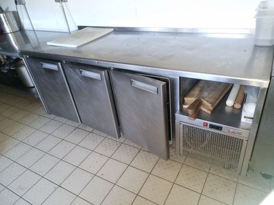 une cuisine équipée d'un plan de travail en inox et de deux réfrigérateurs