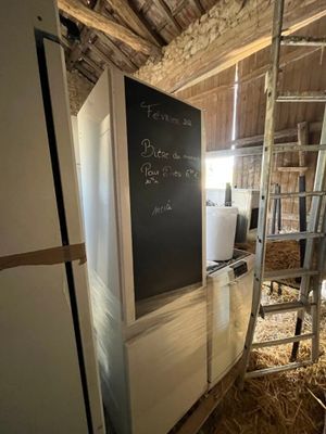 un réfrigérateur dans une grange, avec un tableau noir sur la porte