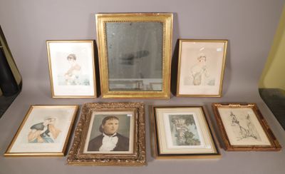 de nombreux tableaux encadrés posés sur une table, à côté d'un miroir