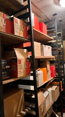 des cartons sont empilés sur des étagères dans une pièce où se trouve une échelle