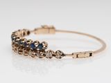 a close up of a gold bracelet with blue and white stones