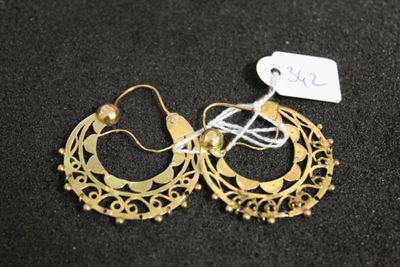 deux paires de boucles d'oreilles créoles en or posées sur une surface noire