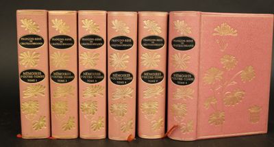 quatre livres roses ornés de motifs à la feuille d'or, posés sur une table