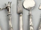 five pieces of silverware including a knife, spoon, and spoon rest