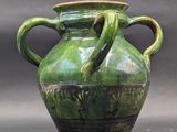 a large green vase with two handles on a table