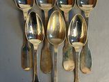 six silver spoons are arranged in a row on a gray surface