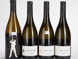quatre bouteilles de vin sont alignées sur une surface blanche