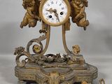 a gold clock with cherensils and angels on it