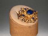 an image of a gold ring with a blue stone surrounded by pearls