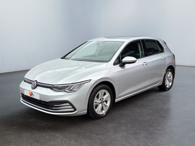 Une Volkswagen Golf argentée est garée dans une pièce blanche
