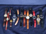 Plusieurs modèles de montres sont alignés sur un tissu bleu