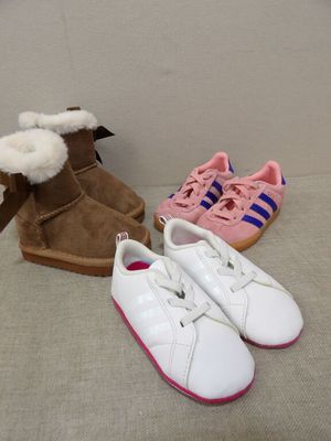 trois paires de chaussures blanches et roses posées sur un lit