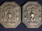 two silver medallions depicting an angel and a man