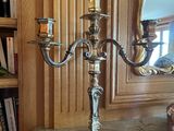 un candélabre en argent avec deux bougies, posé sur une table en marbre