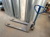 a blue hand truck sitting in front of a stack of metal pipes