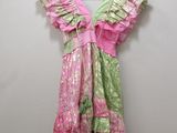 pink and green dress hanging on a hanger against a white wall