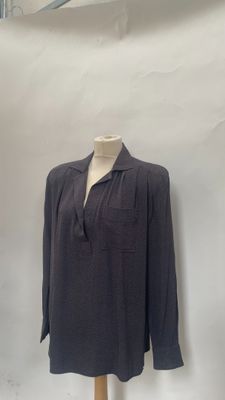 grey shirt on a mannequin stand in front of a white wall