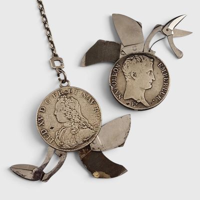 une paire de ciseaux et une pièce de monnaie attachée à une chaîne